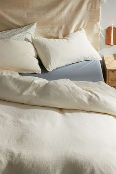 an unmade bed with white sheets and pillows