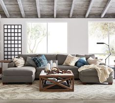 a living room filled with lots of furniture next to a large window and a wooden coffee table