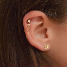 a woman's ear is shown with two piercings attached to the back of her ear