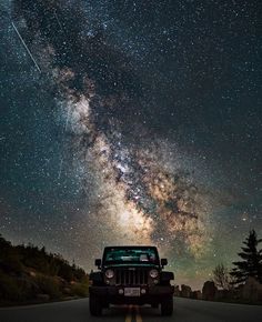 a jeep driving down a road under the stars