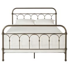 an iron bed frame with white sheets and pillows on top of the headboard, in front of a white background