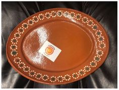 a brown plate with an orange and green design on the rim is sitting on a black leather chair