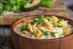 a wooden bowl filled with oatmeal topped with cheese and green garnish