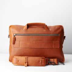 a brown leather briefcase sitting on top of a white table