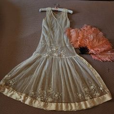 a dress and feather on the floor next to a piece of clothing that has been worn