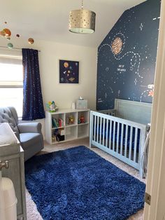 a baby's room with a blue rug and white crib in the corner