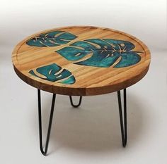 a wooden table with blue leaves painted on the top and black hairpinks legs