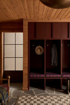 a room with wooden paneling and checkered rugs on the floor next to a bench