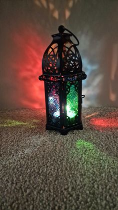 a decorative lantern is sitting on the floor in front of a wall with colored lights