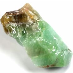 a piece of green and brown rock sitting on top of a white surface