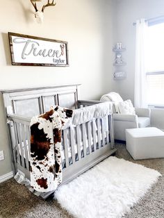 a baby's room with a cow rug on the floor and a crib