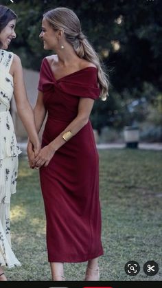 two women in dresses holding hands and looking at each other