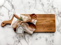 a wooden cutting board with utensils on it and a tag tied to the handle