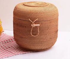 a large woven basket sitting on top of a table next to flowers and a vase