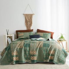 a bed with green and brown bedspread in a room next to a white wall