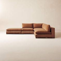 a brown sectional couch sitting on top of a white floor in front of a wall