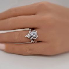 a woman's hand with a diamond ring on top of her finger and the other hand holding an engagement ring