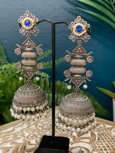 This silver replica statement jhumki earring is crafted with exquisite detail and superior quality. With a combination of kemp stone, kundan work, and pearl drop, these lightweight earrings are sure to be a stylish statement piece. About 4.5inch long and 1.5 inch wide Kundan Work, Jhumki Earrings, Lightweight Earrings, Red Blue Green, Light Weight Earrings, Pearl Drop, Statement Pieces, Red And Blue, Stone