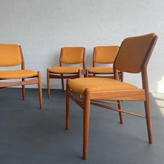 four chairs sitting next to each other in front of a white wall and cement floor