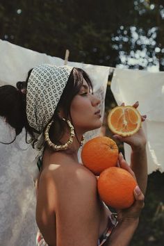 a woman holding two oranges in her hand