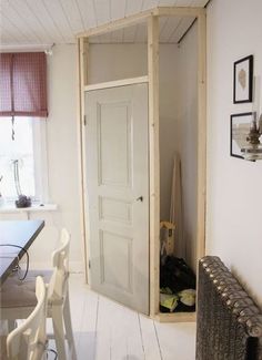 an open door in the corner of a room next to a table with chairs and pictures on the wall