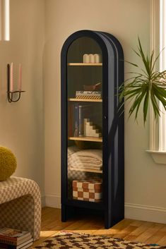 a corner cabinet in the corner of a room with a potted plant next to it