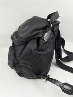 This vintage cult backpack from Prada is the ultimate throwback bag. When Prada released its original nylon backpack in 1984 it was an instant hit. This nylon backpack with a modern, minimalist design is decorated with the Prada enamel triangle logo. Underneath the flap with a leather strap and buckle, is a drawstring closure. There are two adjustable webbing shoulder straps with Prada branded buckles and leather trim. There are two buckled pockets on the front. Inside features the iconic Prada logo lining and an interior zipped pocket for valuables. Lightweight, super cool yet durable and easy to wipe down! The backpack is in very good overall condition with some minor signs of wear. Please view all photos before buying to see the wear. Height: 26cm Width: 23cm Depth: 12.5cm Modern Minimalist Design, Prada Nylon, Prada Logo, Logo Line, Triangle Logo, Diaper Backpack, Casual Backpack, Prada Bag, Leather Trim