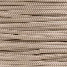 a close up view of a coil of beige colored cord with white thread on the end