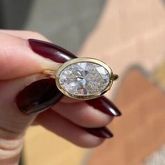 a close up of a person holding a ring with a diamond on the middle of it