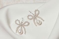 Beautifully simple yet unique pretty bow bridal earrings, handmade using top quality round glass pearls with freshwater teardrop pearls.  The earrings are available in silver, gold, or rose gold plated finish, or you can opt for a more luxurious finish of sterling silver, 14k gold fill, or 14k rose gold fill. The earrings measure approximately 1" in length. Please note that this design incorporates natural freshwater pearls, the beauty of which means each one is unique,  and therefore slight var White Bow Earrings For Wedding, Wedding Pearl Drop Earrings With Bow, White Pearl Earrings With Bow For Wedding, Formal Pearl Earrings With Bow, Formal Pearl Earrings With Bow Detail, White Bow Pearl Drop Earrings, Elegant Bow Jewelry For Weddings, Elegant Wedding Jewelry With Bow, Elegant Bow Pearl Earrings