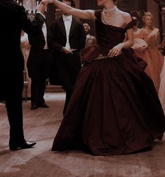 a man in a tuxedo is dancing with a woman in a brown dress