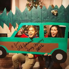 two people holding up a cardboard christmas truck