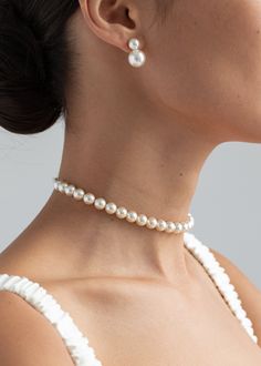 a woman wearing a necklace with pearls on the neck and in front of her ear