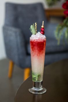 a tall glass filled with ice and garnish on top of a wooden table