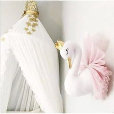 a white swan with a gold crown hanging on the wall next to a canopy bed