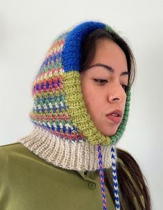 a woman wearing a multicolored knitted hat and neckwarf with braids