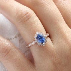 a woman's engagement ring with a blue sapphire and white diamonds on her finger