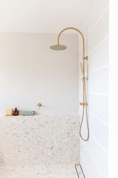 a white bathroom with a shower head and hand held shower faucet next to the bathtub