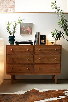 a wooden dresser sitting next to a plant in a living room