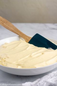 a white bowl filled with frosting and a wooden spatula on top of it