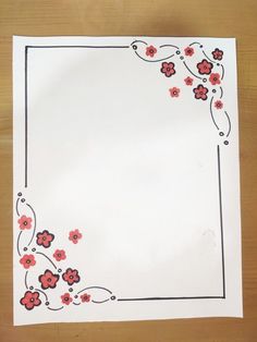 a piece of paper with red and black flowers on it, sitting on top of a wooden table