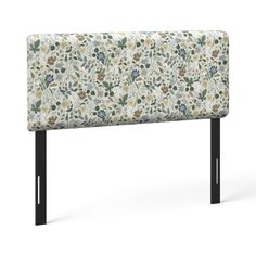 an upholstered headboard with flowers and leaves on the back, against a white background