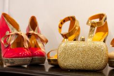 four pairs of shoes and a purse sitting on a shelf in front of a mirror