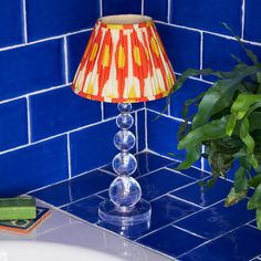 a lamp sitting on top of a blue counter next to a potted green plant