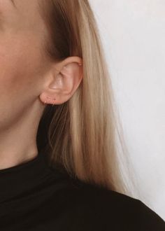 a close up of a person wearing earrings and a black shirt with white writing on it