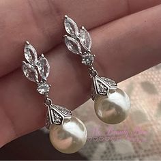 a pair of earrings with pearls and leaves on the end of each earpieces