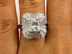 a woman's engagement ring with a cushion cut diamond in the center and shoulders