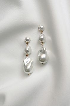 two pairs of pearl earrings sitting on top of a white cloth