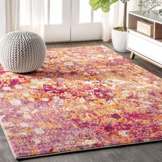 a colorful area rug in a living room with a large vase on the floor next to it