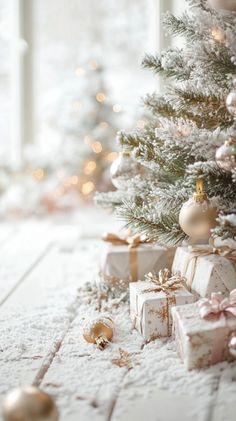 a christmas tree with presents under it in front of a window and snow on the ground